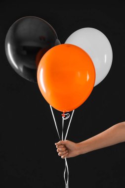 Siyah arka planda cadılar bayramı balonları olan kadın.