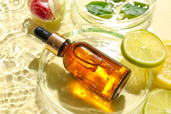 Bottle of vitamin C serum in water on color background, closeup