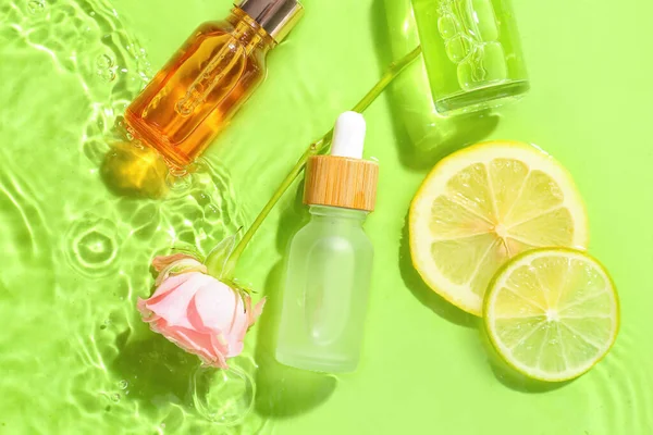 Bottles of vitamin C serum and rose flower in water on color background