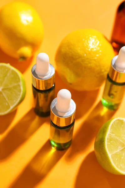 Bottles of vitamin C serum and citrus fruits on color background