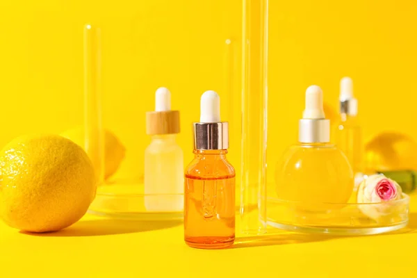 Bottles of vitamin C serum on yellow background