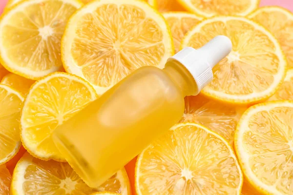 Bottle of vitamin C serum on lemon slices, closeup