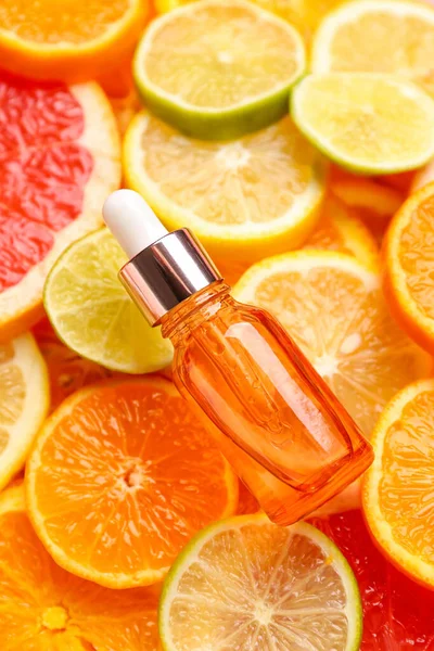 Bottle with vitamin C serum on slices of citrus fruits