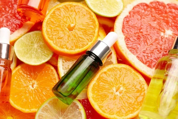 Bottles with vitamin C serum on slices of citrus fruits