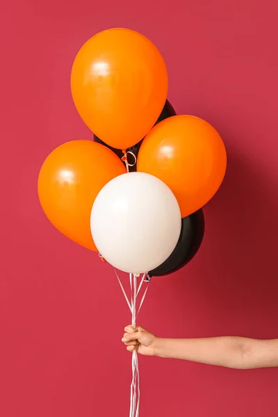 Woman with Halloween balloons on red background