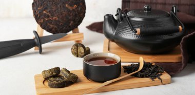 Bir fincan sıcak puer çayı ve çaydanlık beyaz masada.