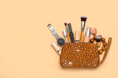 Makyaj ürünleri ve bej arka planda aksesuarlarla dolu kozmetik çanta