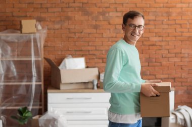 Taşındığı gün mutfakta karton kutulu genç bir adam.