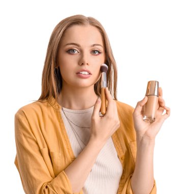 Makyaj temeli olan ve beyaz arka planı fırçalayan genç bir güzellik blogcusu