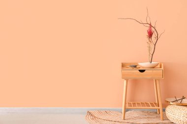 Bej duvarın yanındaki masada güzel ikebana 'lı kase.