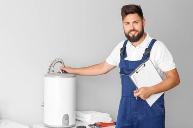 Tuvaletteki kazanın yanında panosu olan erkek tesisatçı.