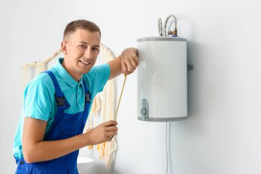 Erkek tesisatçı banyoya kazan kuruyor.