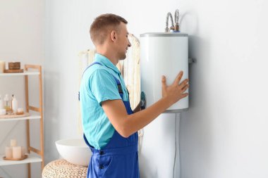 Erkek tesisatçı banyoya kazan kuruyor.