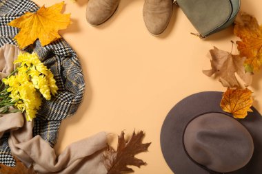 Şık kadın aksesuarlarından yapılmış çerçeve, kasımpatı çiçekleri ve bej arka planda sonbahar yaprakları