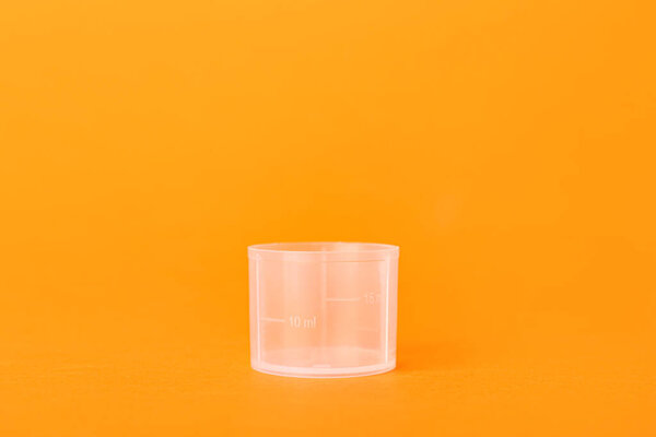 Пустой измерительный стакан на оранжевом фоне