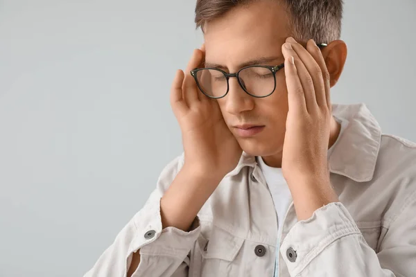 Stressed young man with eyeglasses on light background, closeup