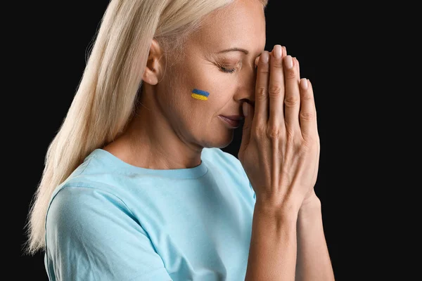Dojrzała Kobieta Narysowaną Flagą Ukrainy Modląca Się Czarnym Tle Zbliżenie — Zdjęcie stockowe