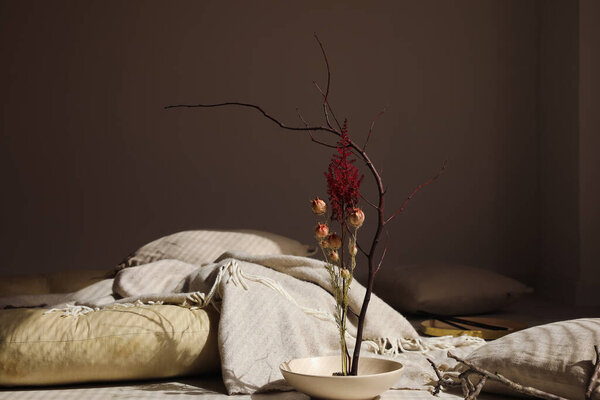 Bowl with beautiful ikebana on floor in dark room