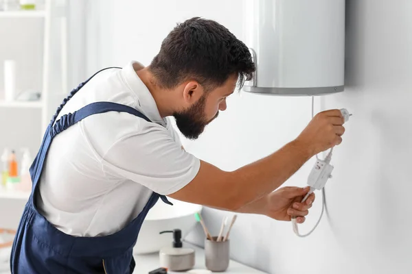 Male plumber with boiler\'s plug in bathroom
