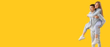 Sarı arka planda kot elbiseli şık genç çift mesaj için yer var.