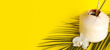 Samanlı taze hindistan cevizi, orkide çiçeği ve sarı arkaplanda yazı için boşluk olan palmiye yaprağı.