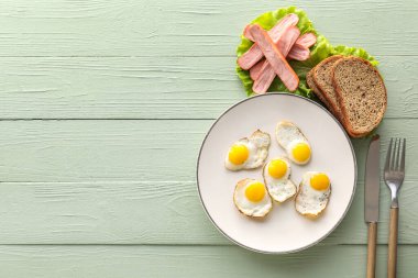 Kızarmış bıldırcın yumurtası, sosis ve ahşap kaplamalı ekmek tabağı.