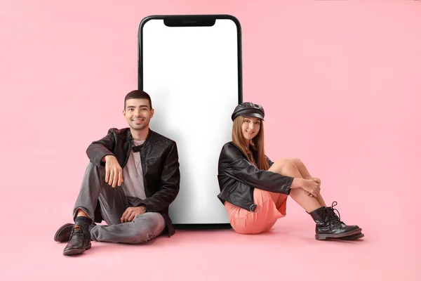 Κομψό Νεαρό Ζευγάρι Κάθεται Κοντά Μεγάλο Smartphone Ροζ Φόντο — Φωτογραφία Αρχείου