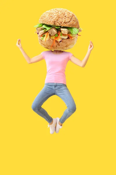 Jumping meditating woman with tasty doner kebab in bun instead of her head on yellow background