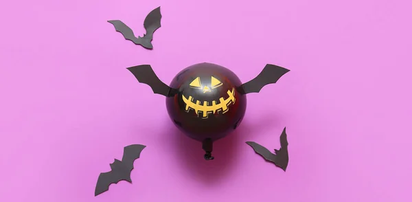 Funny Halloween balloon and paper bats on lilac background