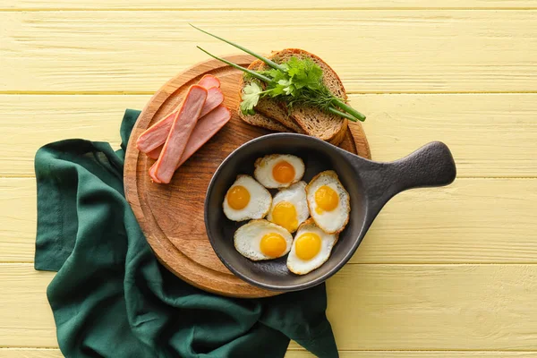 平底锅上放满了美味的炸鹌鹑蛋和香肠 配上彩色木制背景的木板 — 图库照片