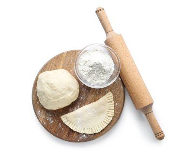 Hamurlu tahta, çiğ çeburek, bir kase un ve beyaz arka planda merdane.