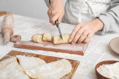 Işık duvarının yakınındaki masada çizer için hamur kesen kadın.