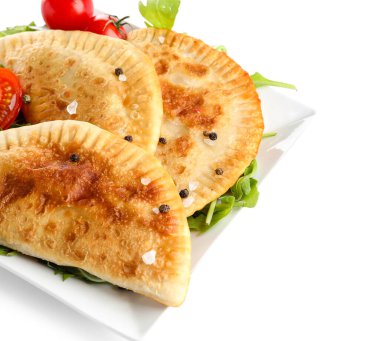 Beyaz arka planda lezzetli chebureks ve sebzeli tabaklar, yakın plan.