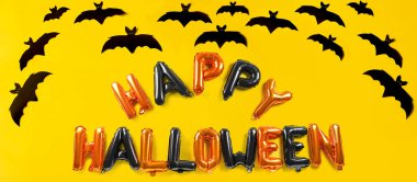 Balonlardan ve sarı arkaplandaki kağıt yarasalardan yapılmış Cadılar Bayramınız kutlu olsun.