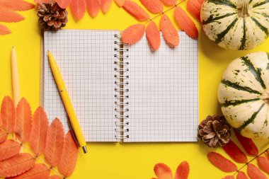 Sarı arkaplanda açık defter, kalem ve sonbahar dekoru