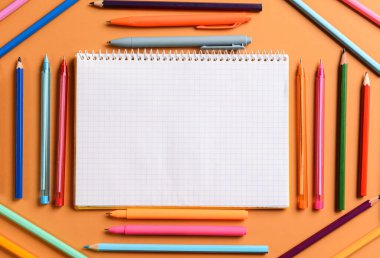 Renk arkaplan üzerinde farklı kalem ve kalemlerle dizüstü bilgisayarı olan kompozisyon