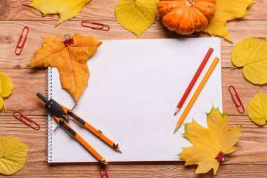 Not defteri, pusula, kalem ve ahşap arka planda sonbahar dekoru.