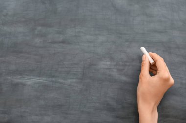 Okul tahtasına karşı tebeşirli kadın eli.