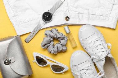 Şık kadın kıyafetleri, ipek toka ve sarı arka planda farklı aksesuarlar.