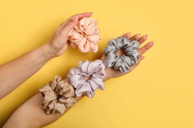 Sarı arka planda farklı ipek tokaları olan kadın elleri