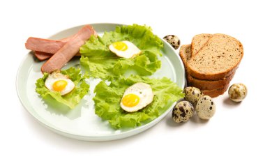 Beyaz arka planda lezzetli kızarmış bıldırcın yumurtası ve sosis tabağı.