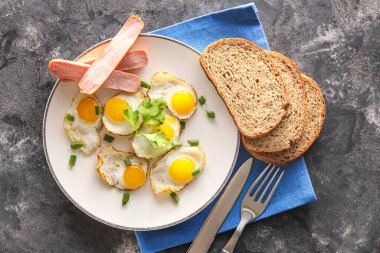 Lezzetli kızarmış bıldırcın yumurtası, sosis ve arkaplanda ekmek tabağı.