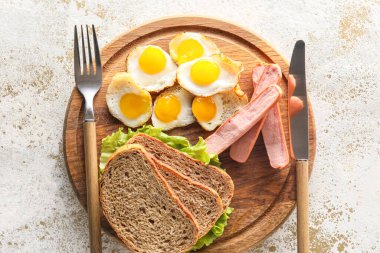 Hafif arka planda kızarmış bıldırcın yumurtası, ekmek ve sosisli ahşap tahta pano, yakın plan.