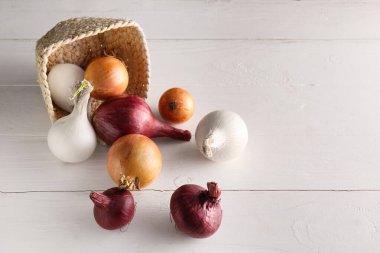 Tersine çevrilmiş sepet ve hafif ahşap arka planda taze soğan.