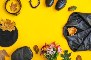 Şık kıyafetler, ayakkabılar, aksesuarlar, çiçekler ve sarı arka planda sonbahar yapraklarından yapılmış çerçeve