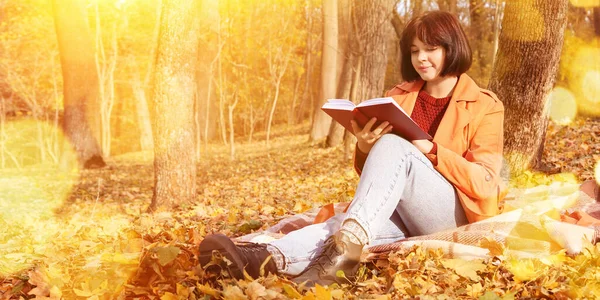 Młoda Kobieta Siedzi Kratę Pobliżu Drzewa Czyta Książkę Jesiennym Parku — Zdjęcie stockowe