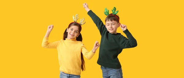 Zabawny Taniec Małych Dzieci Rogami Reniferów Żółtym Tle — Zdjęcie stockowe