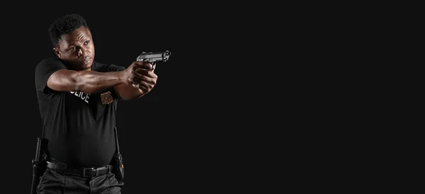 African-American police officer with gun on dark background with space for text