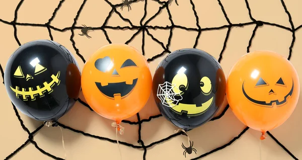 Halloween balloons and spider web on beige background