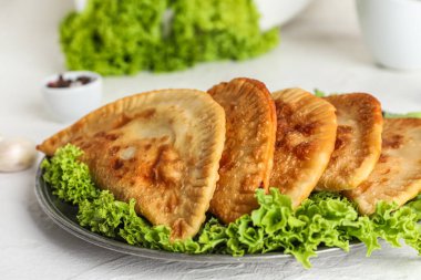 Hafif arka planda lezzetli chebureks ve marul tabağı, yakın plan.